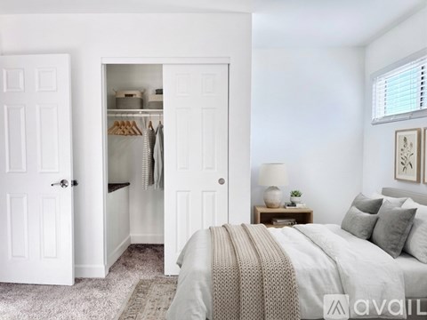 A bedroom with a large bed and a closet with an open door.