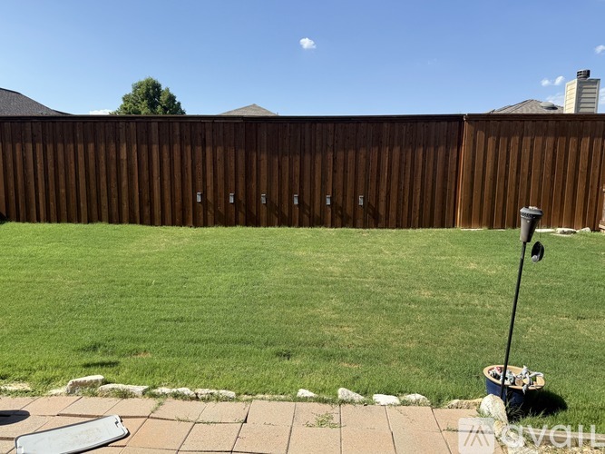 A backyard with a wooden fence and a green lawn.