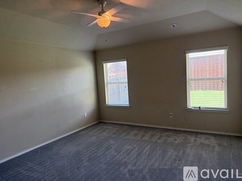 A room with a ceiling fan and two windows.