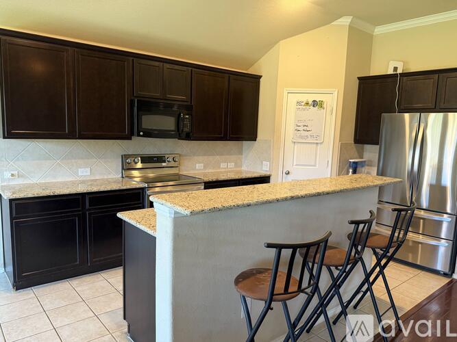 A kitchen with black cabinets and a granite countertop.