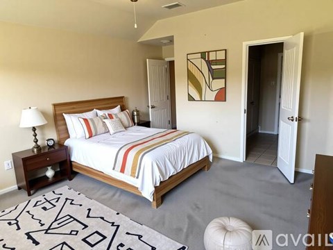 A bedroom with a large bed and a patterned rug.