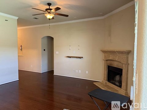 A living room with a fireplace and a fan on the ceiling.