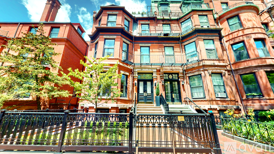A large red brick building with a black iron fence in front.