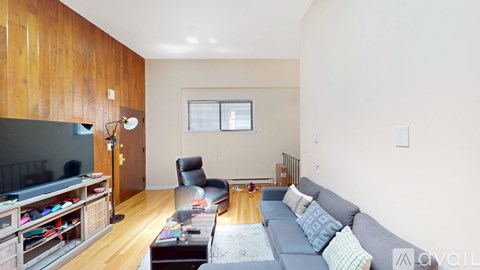 A living room with a grey couch and a wooden cabinet.