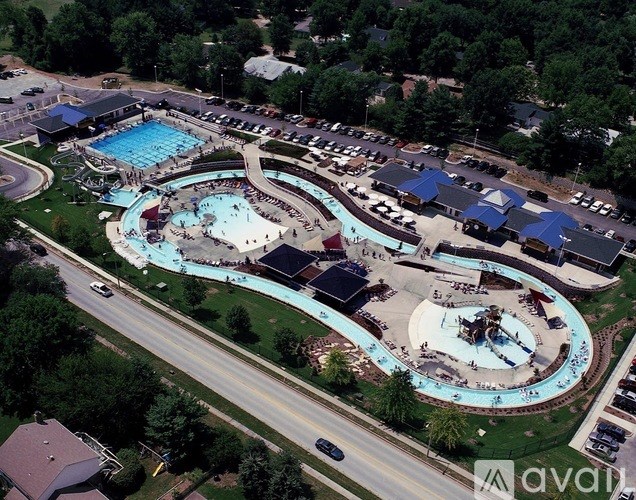 An aerial view of a large outdoor swimming pool complex with a slide, a hot tub, and a water park.