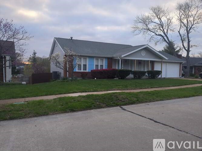 A house with a blue door is surrounded by a green lawn.