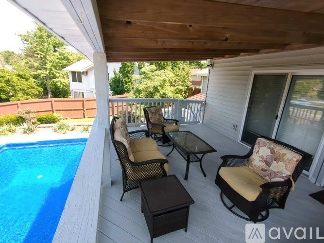 A patio with a table and chairs overlooking a pool.
