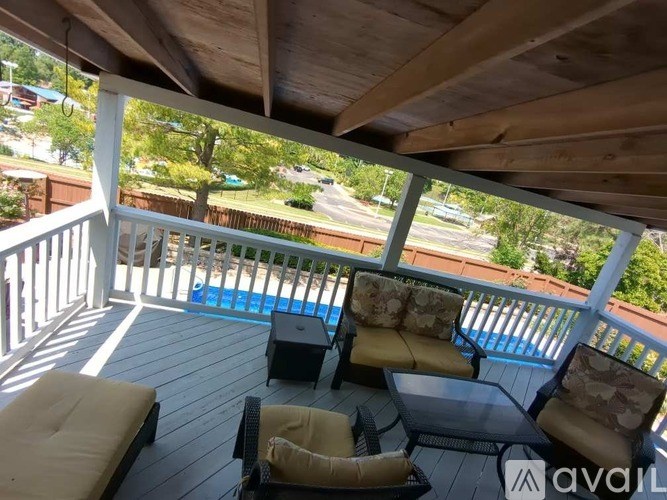 A wooden deck with a table and chairs overlooking a pool.
