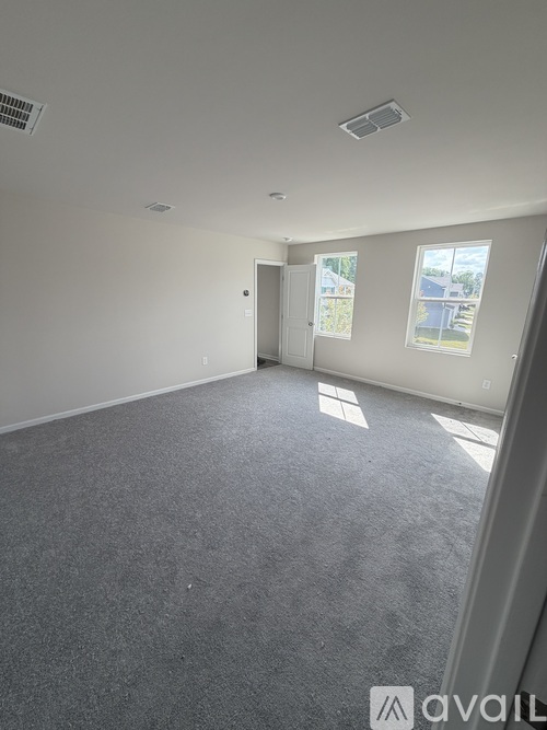 A spacious room with a grey carpet and white walls.