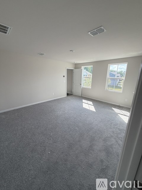 A spacious room with a grey carpet and white walls.