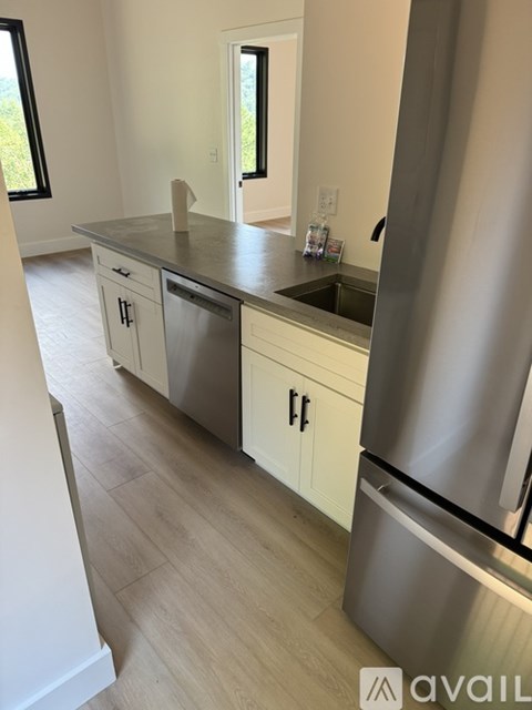 A kitchen with a stainless steel refrigerator and white cabinets.