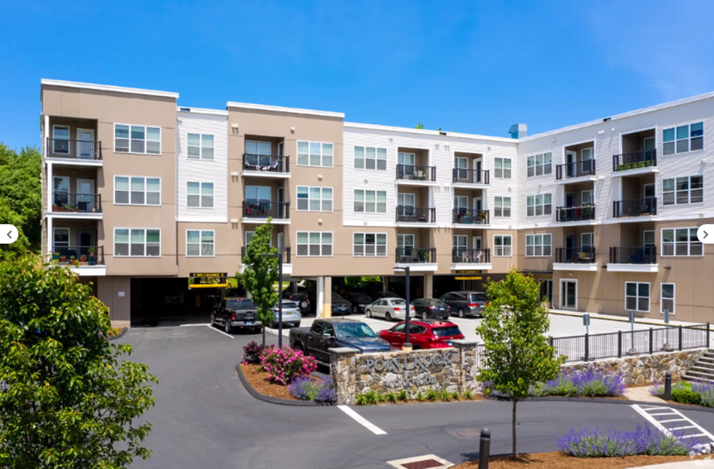 A large apartment complex with a parking lot in front.