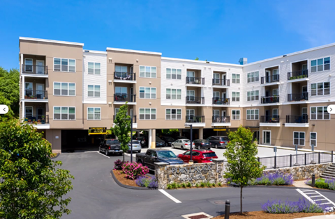 A large apartment complex with a parking lot in front.