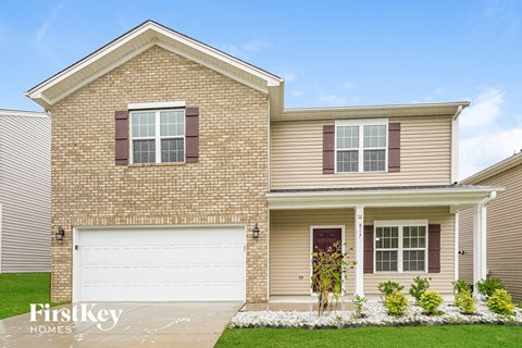 A brick house with a garage door and a flower bed in front.
