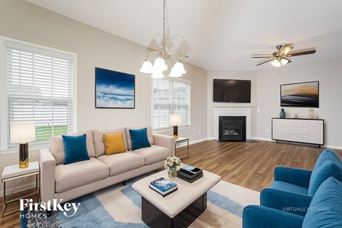 A living room with a white couch and a painting on the wall.