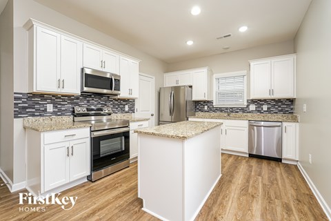 A kitchen with white cabinets and a granite countertop.