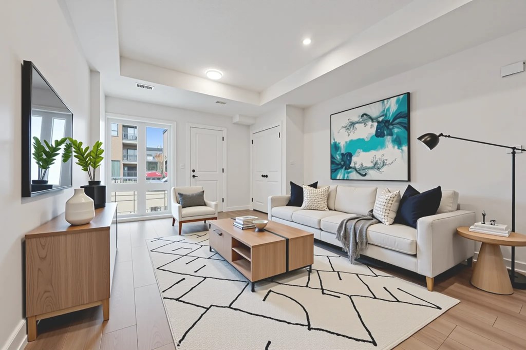 A modern living room with a white sofa, wooden side table, and a large abstract painting on the wall.