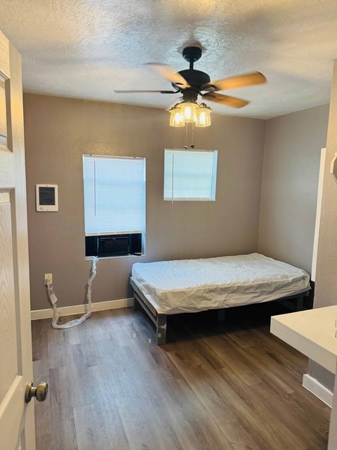 A bedroom with a bed, a window, and a ceiling fan.