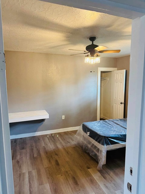 A room with a ceiling fan and a bed covered in plastic.