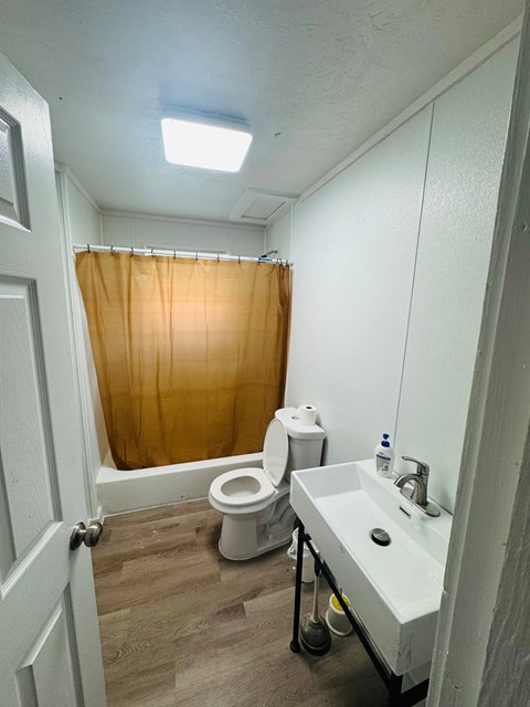 A bathroom with a toilet, sink, and shower curtain.