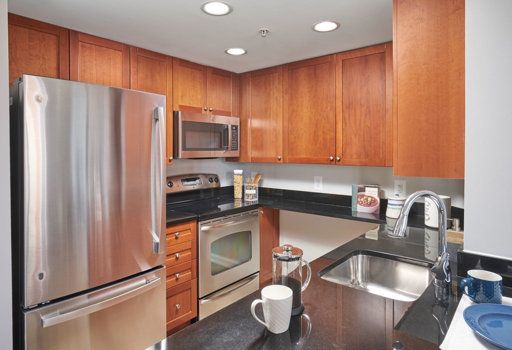 A kitchen with wooden cabinets and a stainless steel refrigerator.