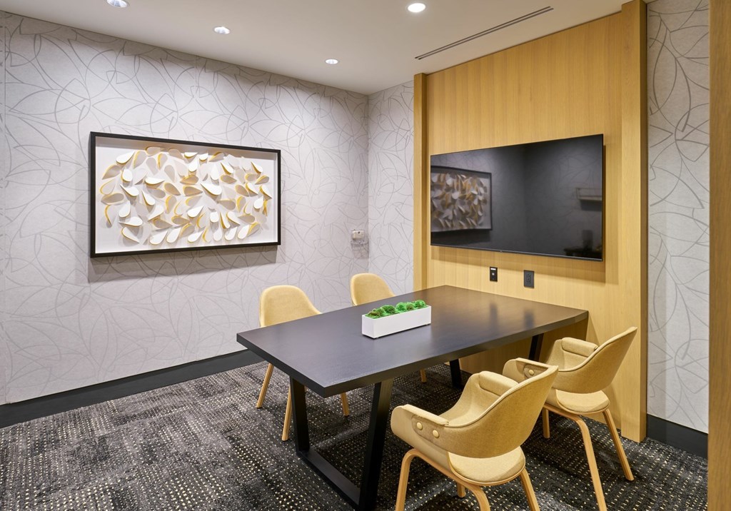 A conference room with a table, chairs, and a television.