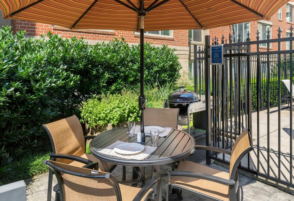 A table set for two with a view of a gate and a building in the background.