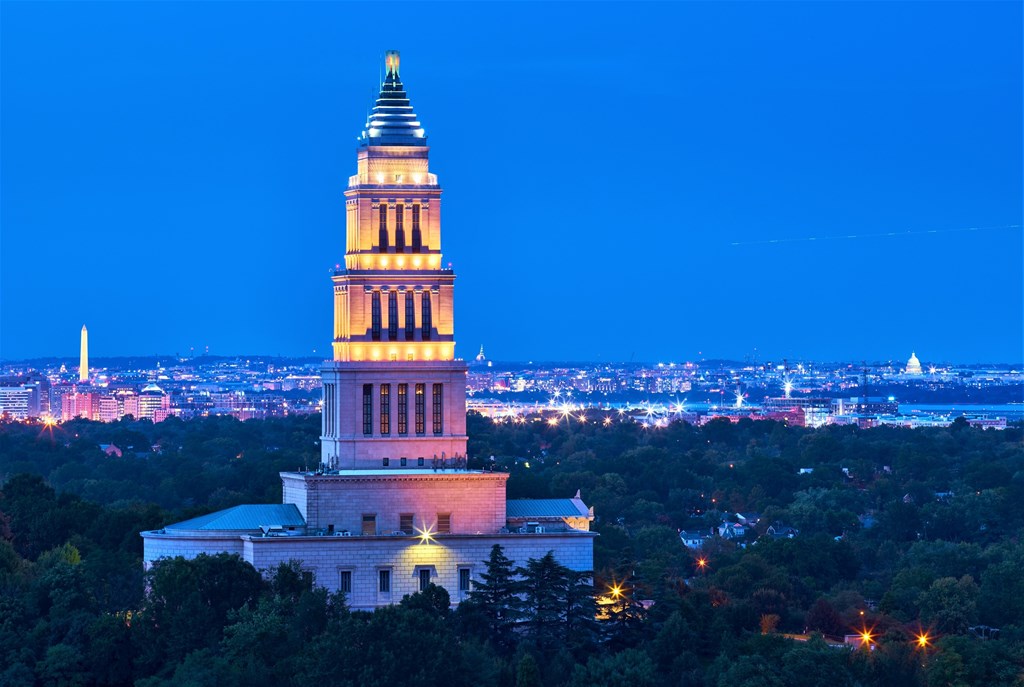 A large white building with a tall spire is lit up at night.