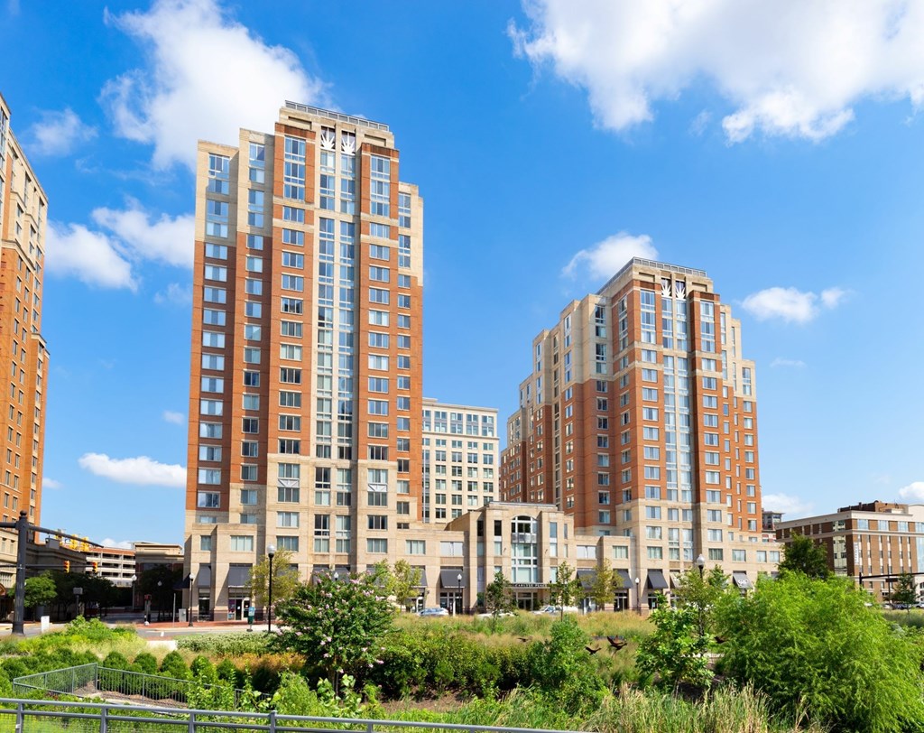 A row of modern apartment buildings are seen in the distance behind a green field.