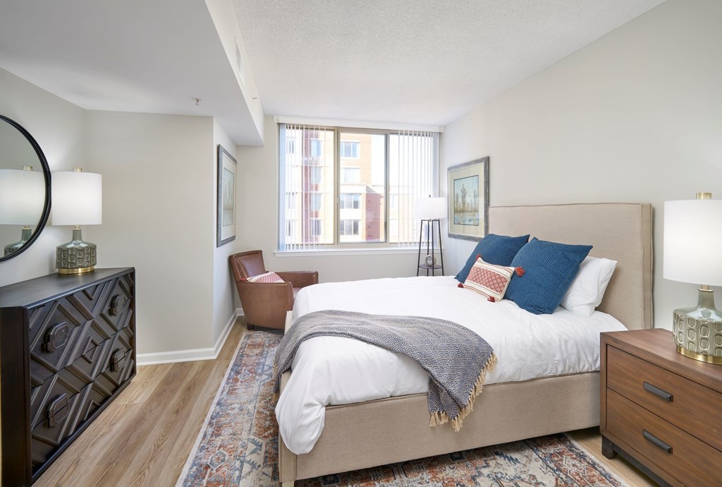 A bedroom with a large bed and a chair.