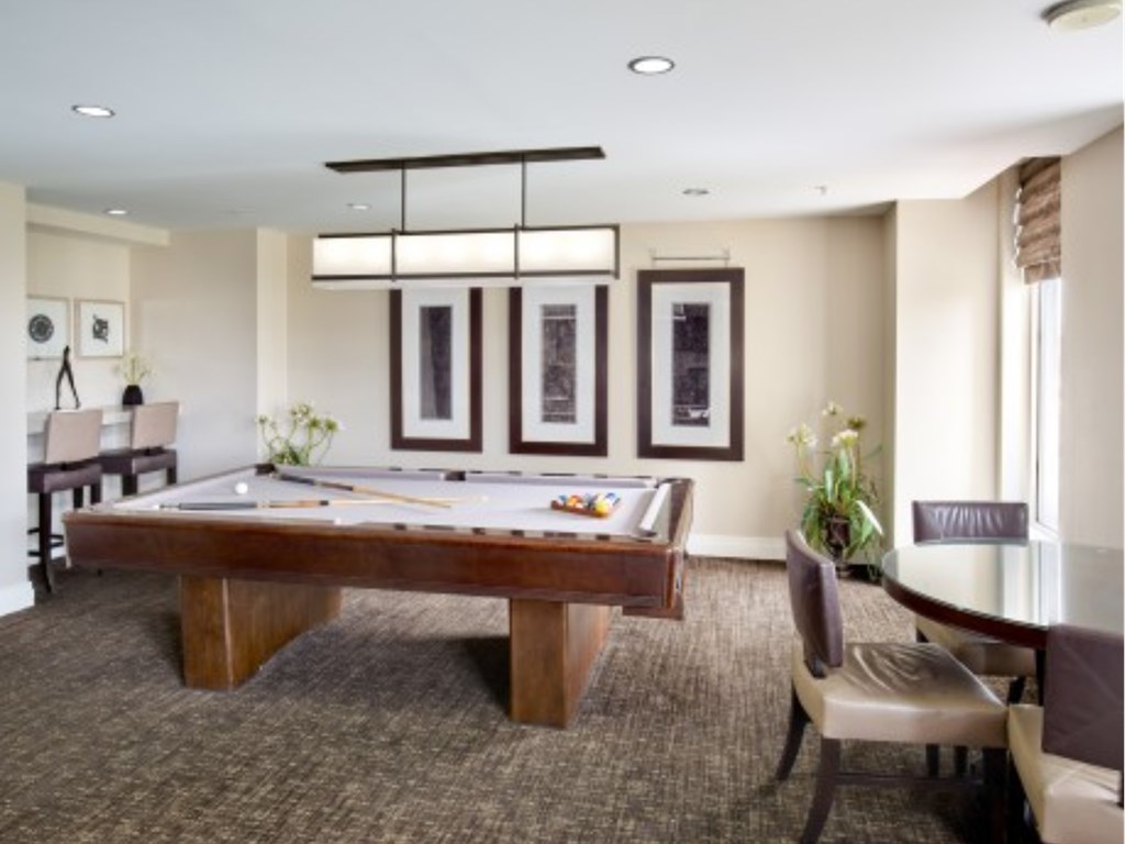 A room with a pool table and chairs.
