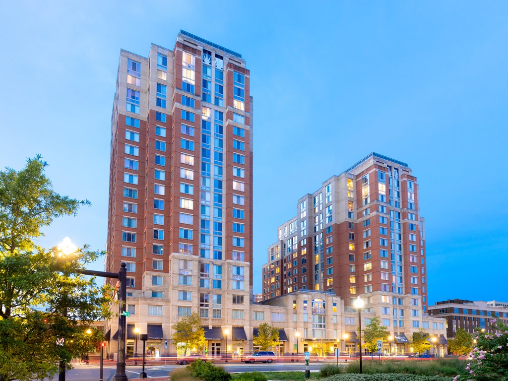 Two tall buildings are lit up at dusk.
