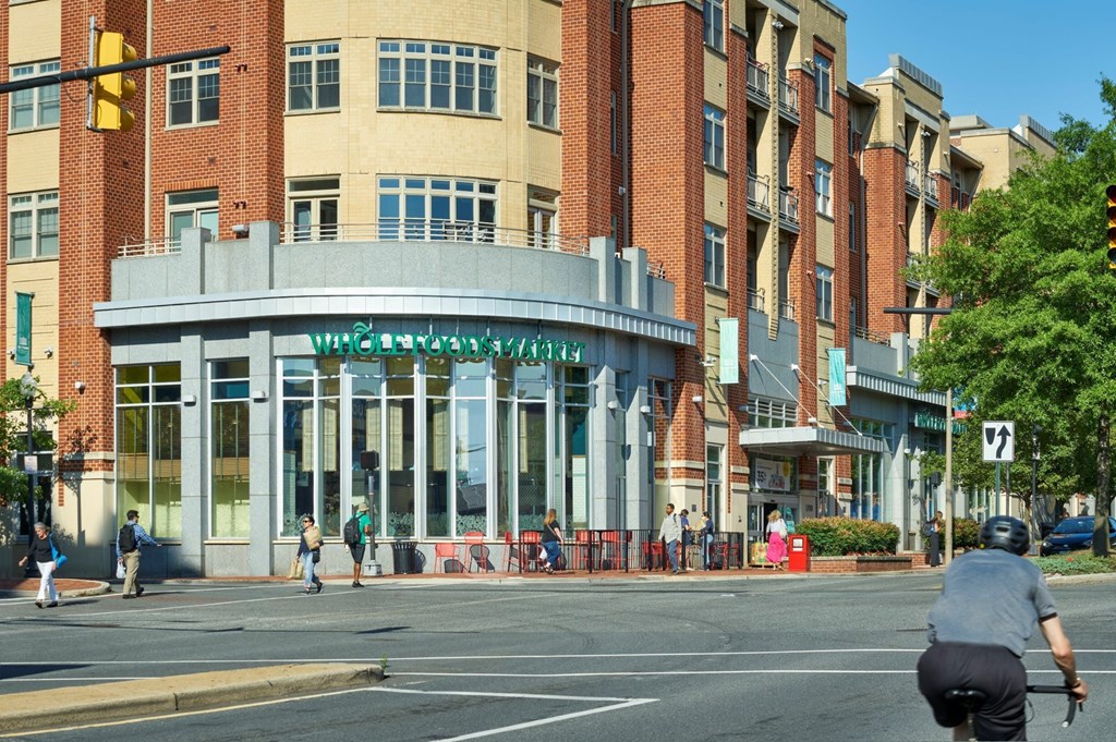 A man is riding a bicycle on a street in front of a building with a sign that reads "The Civic Center."