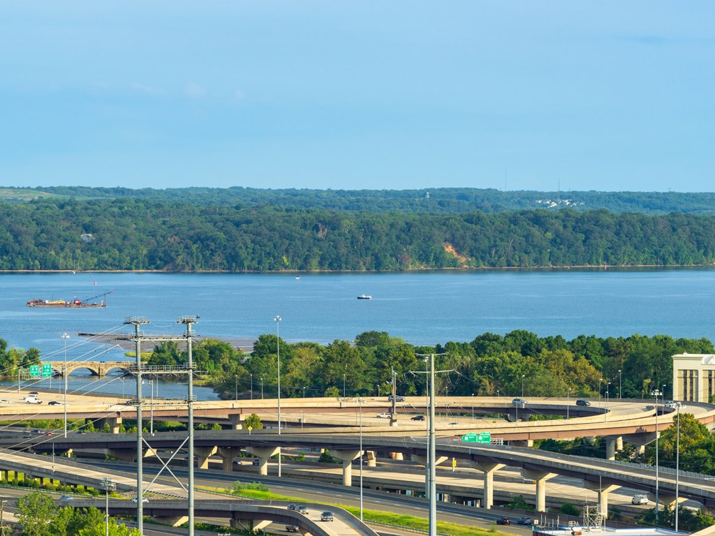 A large highway interchange with a body of water and trees in the background.