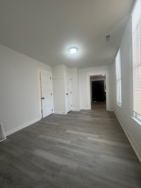A long hallway with a light on the ceiling and a door at the end.