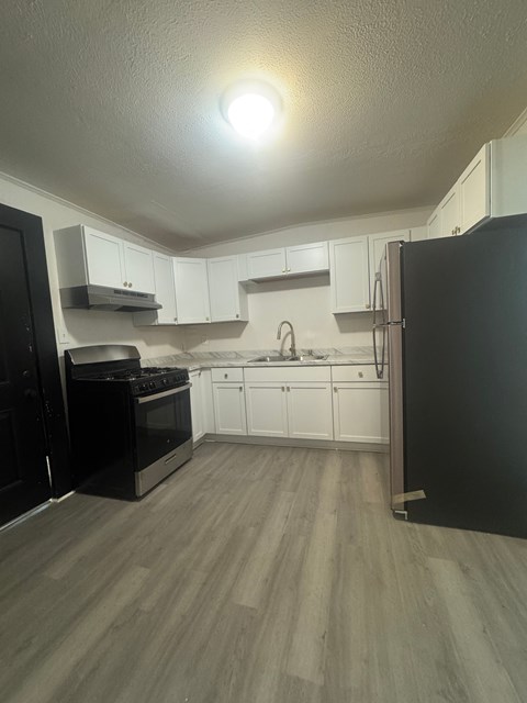 A kitchen with black appliances and white cabinets.