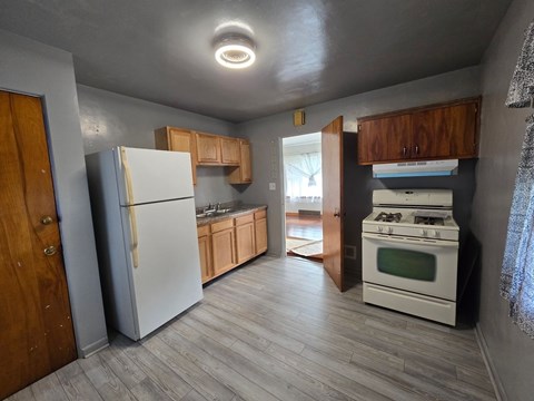 A kitchen with a white refrigerator, white stove, and wooden cabinets.