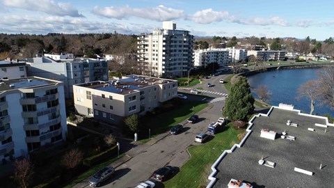 A view of a residential area with apartment buildings, cars parked in a lot, and a body of water.