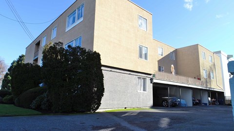 A large beige building with a parking lot in front.
