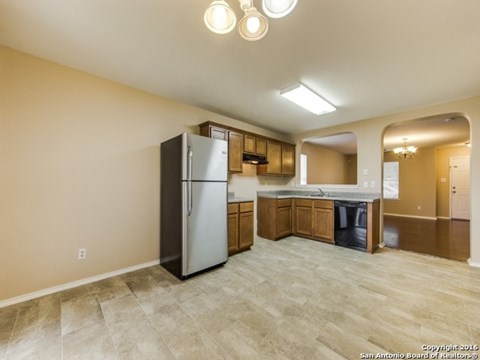 A kitchen with a refrigerator, cabinets, and a countertop.