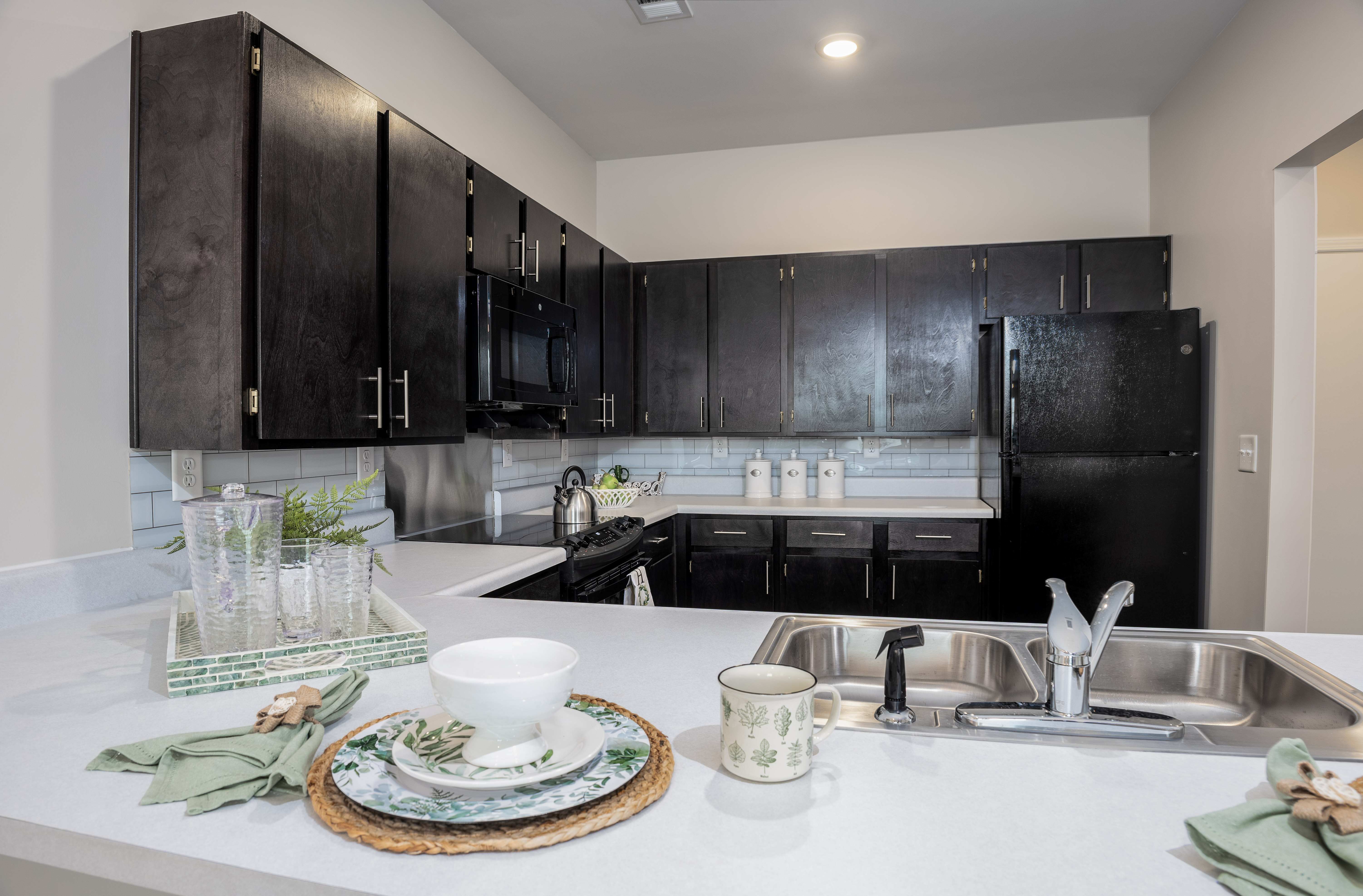 A modern kitchen with black cabinets and a white countertop.