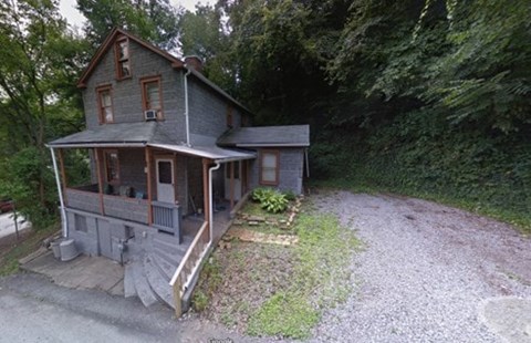 A house with a porch and a gravel driveway in front.