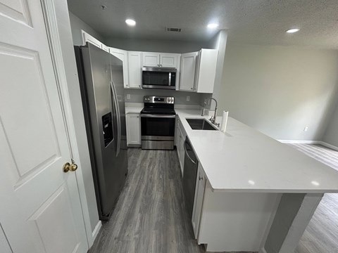 A kitchen with a refrigerator, microwave, oven, and sink.