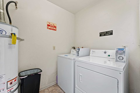 A small laundry room with a washer and dryer and a trash can.