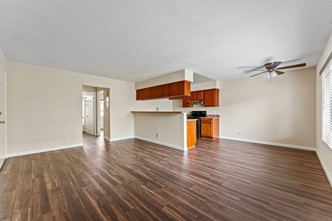 A spacious room with wooden flooring and a ceiling fan.