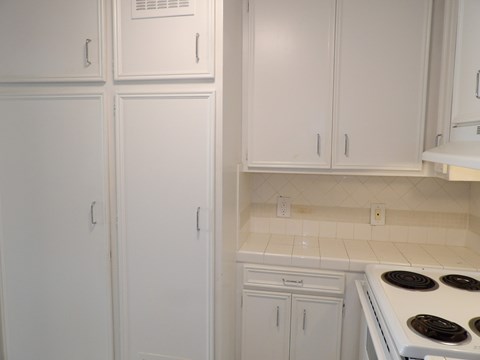 A kitchen with white cabinets and a white stove top.