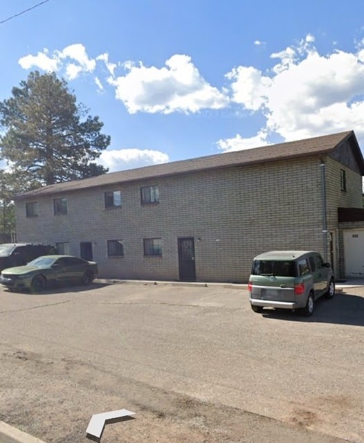 A green van is parked in a lot in front of a brick building.