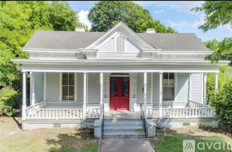 A white house with a red door and a porch.