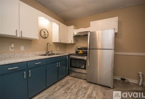 A kitchen with blue cabinets and a stainless steel refrigerator.