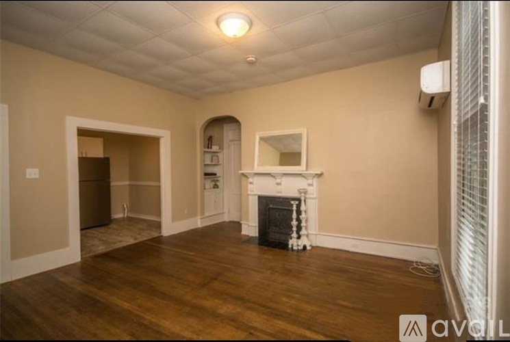 A spacious room with a fireplace and wooden floors.